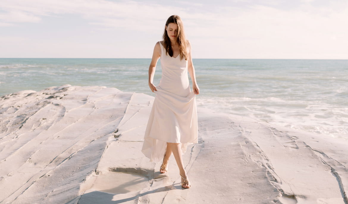 Woman standing with crossed legs in a white dress