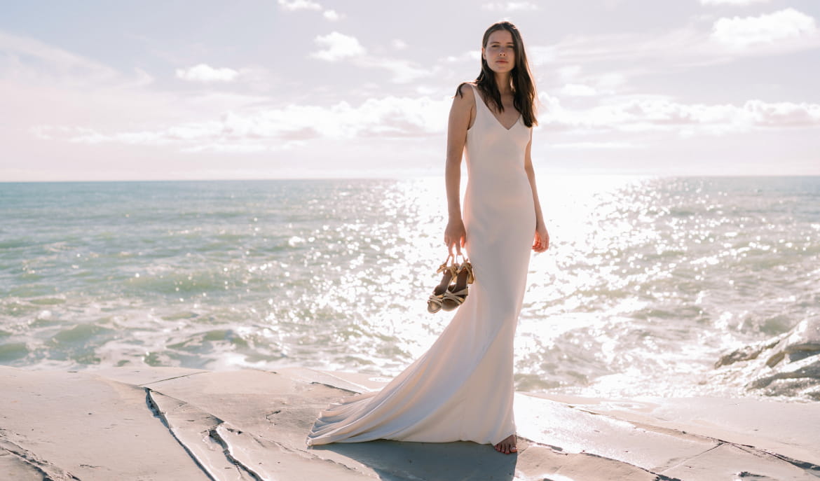 femme debout dos à la mer en robe de mariée