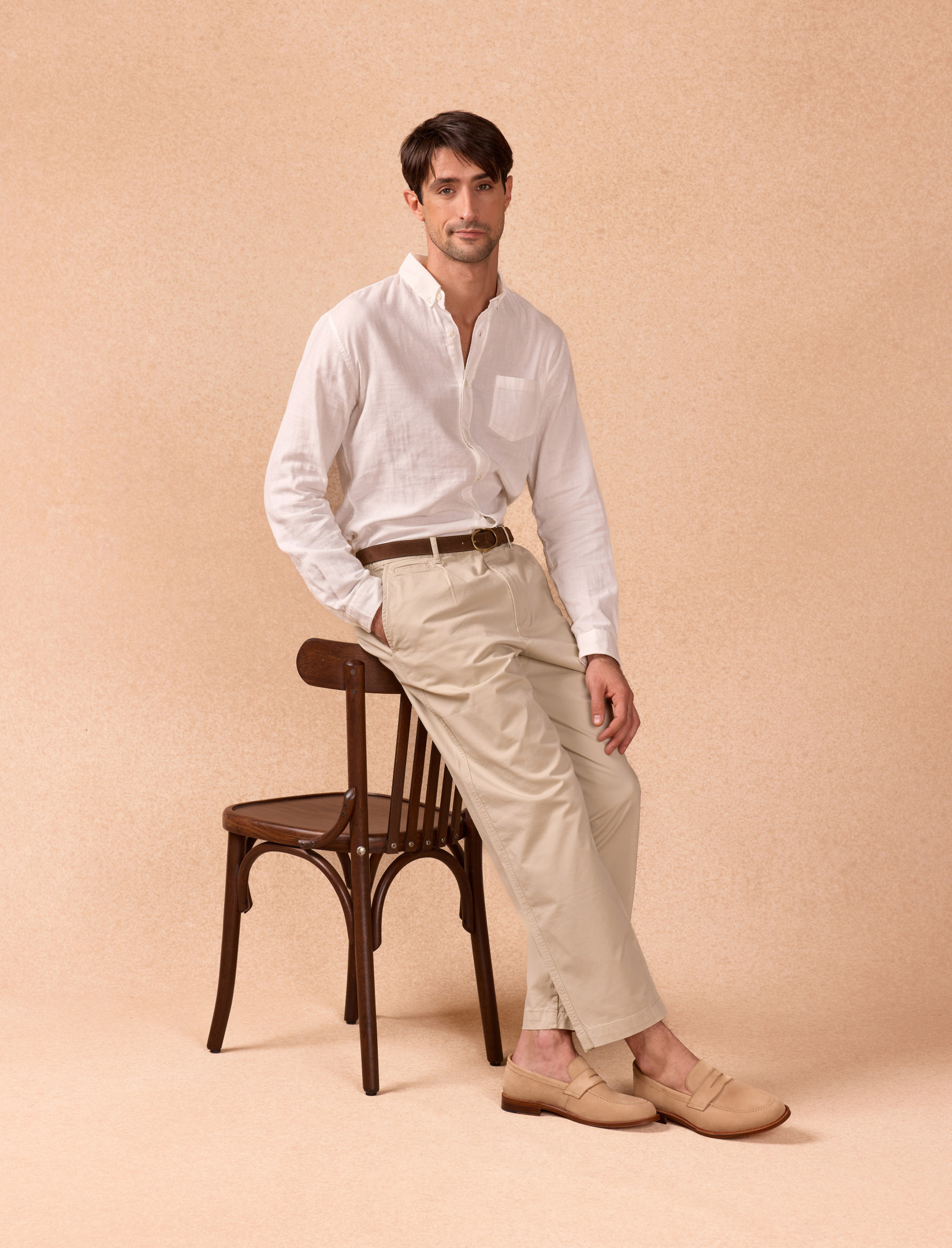 homme assis sur le dos d'une chaise portant des mocassins beige