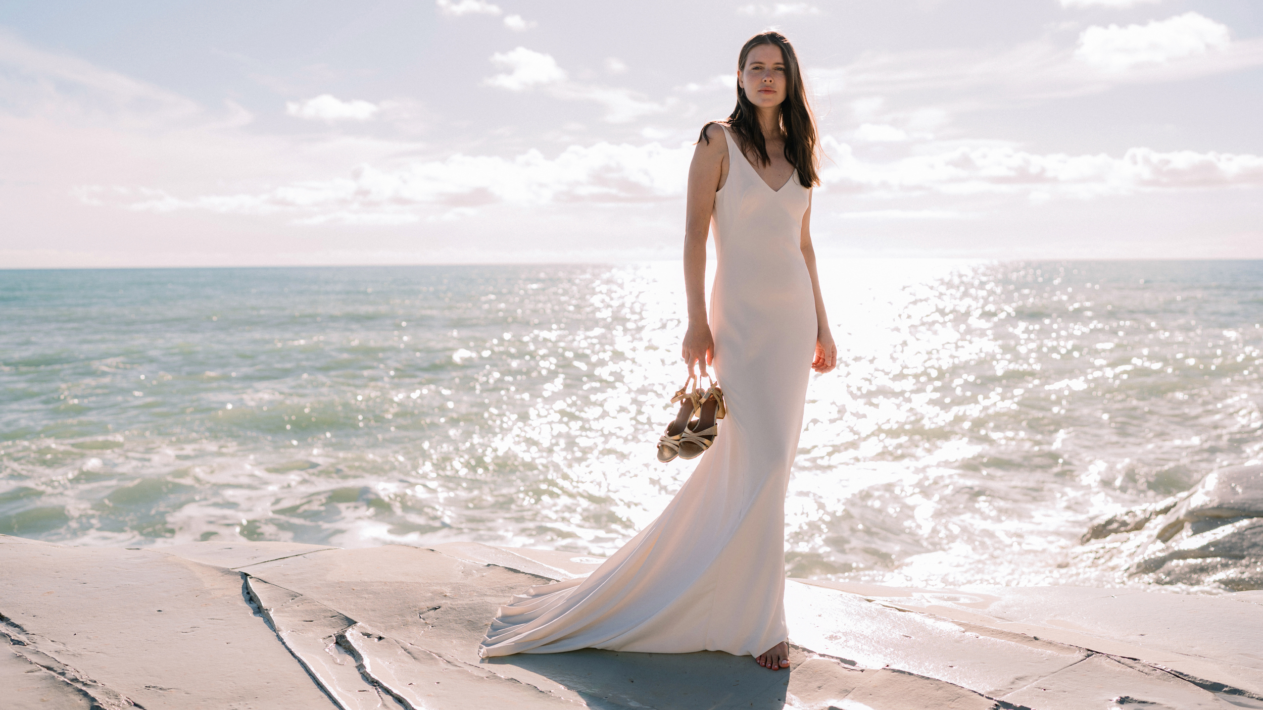 femme debout dos à la mer en robe de mariée