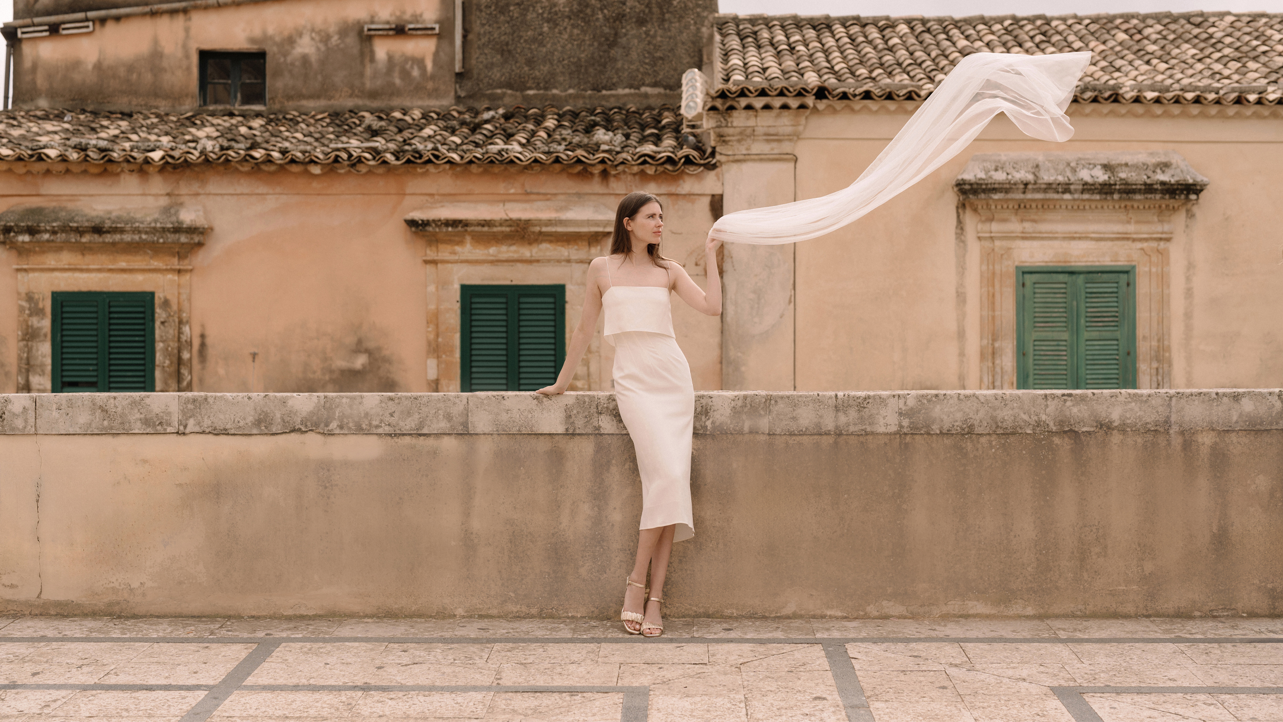 femme en robe de mariée tenant son voile blanc